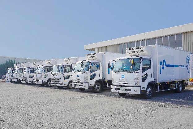 マグチグループのロゴマーク入りの車両が複数台並ぶ風景